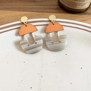Detail view of U-shaped resin earrings with golden accents and marble texture on ceramic tray