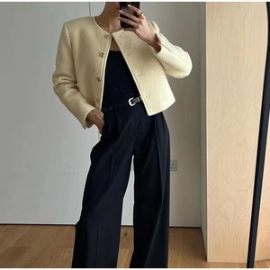 Dettaglio dell'elegante giacca in tweed crema con bottoni dorati e girocollo