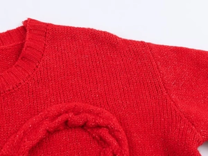 Detail of red cable-knit sweater showing ribbed crew neck and thick textured knit patterns