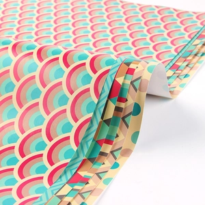 Various patterned gift wrapping paper rolls featuring pink blue and beige fish scale patterns