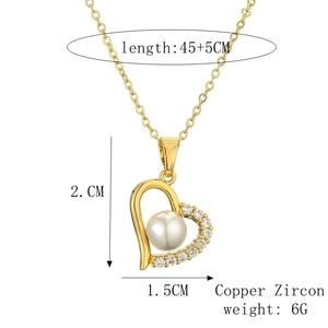Detail of gold heart pendant with center pearl and zircon accents on a chain