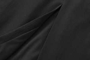 Detailed close-up of side slit design and textured crepe fabric on a black dress