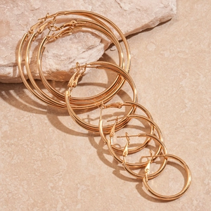 Detailed macro view of five pairs of polished gold hoop earrings in various sizes