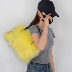 Detail view of a large yellow faux fur tote bag worn by a model in a studio setting
