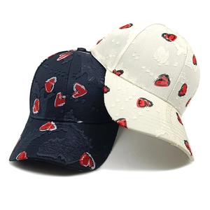 Distressed baseball caps in black and cream featuring red heart patterns and frayed texture