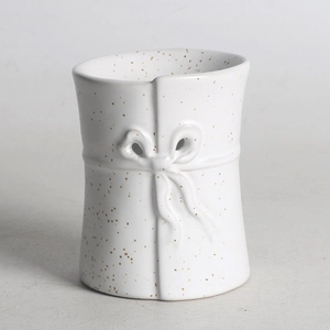 Detailed view of white ceramic jar featuring a decorative bow and textured finish