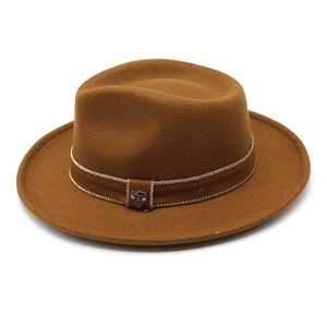 Detailed view of camel wool fedora hat featuring gold chain band and metal shield crest