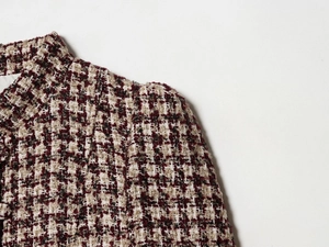 Detailed close-up of burgundy tweed blazer featuring woven texture and notched lapel