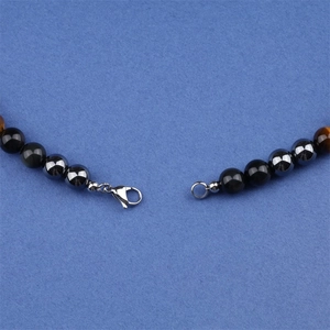 Gedetailleerde macro-opname van de metalen karabijnsluiting op een tijgeroog kralenketting