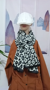 Detail of soft leopard print scarf paired with a white distressed cap on a model