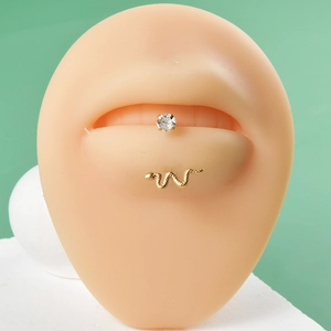 Detailed shot of a gold snake-shaped stud and a clear zircon labret on a silicone lip model