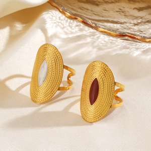 Golden oval rings with white and red stone inlay on silk background