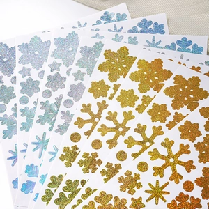 Close-up of glittery gold and blue-purple snowflake stickers for DIY holiday cards