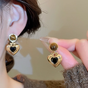 Detailed view of vintage gold heart earrings with tiger eye stone and black heart inlay