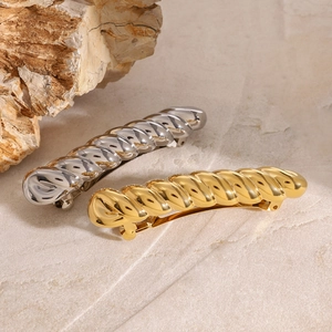 Detailopname van gouden en zilveren haarclips met croissant-textuur op steen