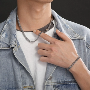 Men's silver Cuban link necklace and bracelet set worn over a blue denim jacket