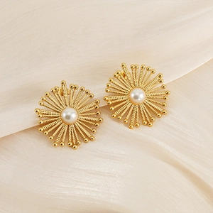 Golden stainless steel sunflower stud earrings with round white pearl on silk background