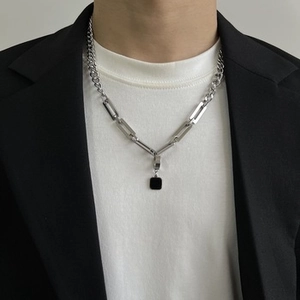 Detail of silver Cuban link necklace with black square pendant on male model