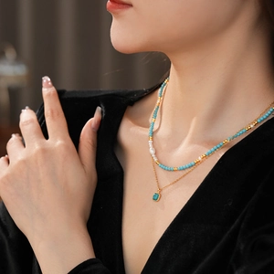 Dettaglio di collana dorata a strati con perle di turchese e perle d'acqua dolce su modella
