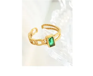 Detail of adjustable gold ring featuring emerald-cut green zircon and Cuban chain texture
