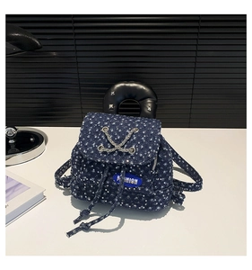 Close-up of denim backpack with floral sequins, metal chain, and star rivet leather handle