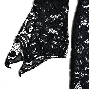 Close-up detail of the intricate black lace fabric on sleeve or hem of the maxi dress