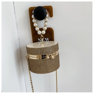 Detail of champagne gold rhinestone cylindrical evening bag with pearl handle and chain