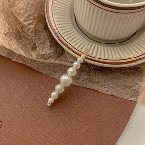 Detailed close-up of a gold pearl hair clip resting on a striped ceramic cup with warm tones