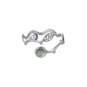 Dettaglio ravvicinato di un anello in argento a forma di ramo con perla e gemma verde brillante