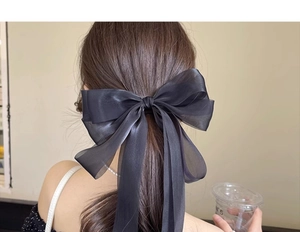 Detail of elegant black oversized sheer ribbon bow hair clip on model back view