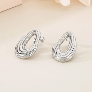 Gros plan de boucles d'oreilles gouttes d'argent minimalistes au design évidé poli