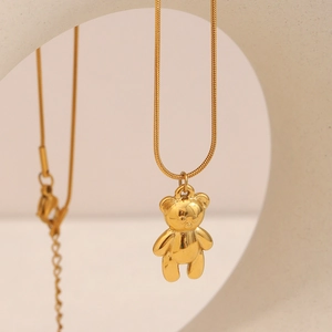 Close-up of a gold-plated 3D teddy bear pendant on a delicate snake chain necklace