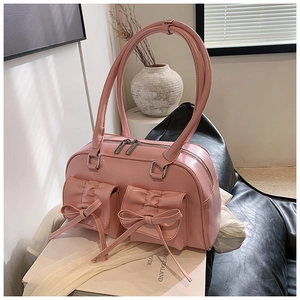 Detailed view of pink bow-knot pockets on faux leather shoulder bag with zip top