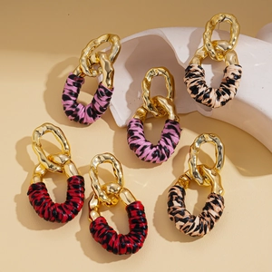 Detail of leopard print fabric earrings with irregular gold metallic hoops on stone props