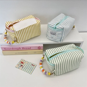 Detail of striped fabric tissue bags with colorful bead handles in blue, yellow and green