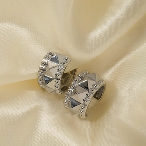 Macro shot of silver C-shaped stud earrings with geometric cone rivets and beaded edges