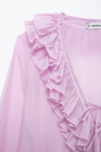 Detail of light purple V-neck shirt featuring layered ruffle edges and delicate tie-up design