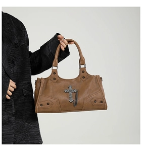 Nahaufnahme der braunen Gothic-Handtasche mit Vintage-Metallkreuz und Nietenketten