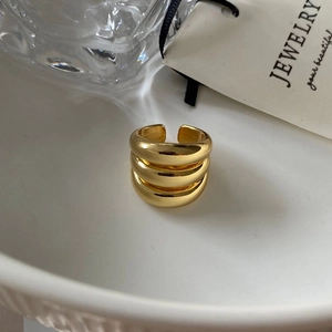 Macro detail of high-polish gold-plated triple layer open ring on white ceramic