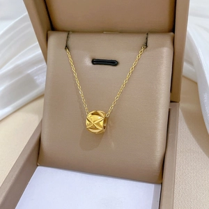 Macro shot of gold-plated cylinder necklace with diamond-cut pattern on gift box