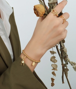 Nahaufnahme von Goldperlenarmband mit Hasenanhänger und Ringen zu olivgrünem Anzug