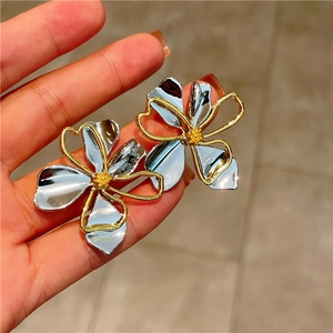 Detailed close-up of two-tone flower earrings with polished silver petals and gold accents