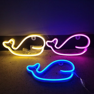 Three whale-shaped LED neon signs in yellow, pink and blue on a concrete surface