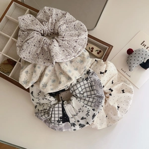 Set of floral and plaid cotton hair scrunchies on a white desk with wooden box