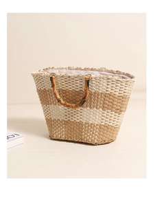 Detail of hand-woven straw tote with elegant bamboo handle and natural striped texture