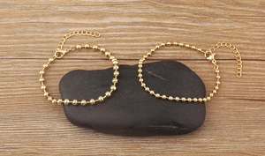 Detail of 18k gold plated bead bracelets with lobster clasp on natural pebbles