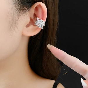 Macro detail of silver flower ear cuff with sparkling zircon stones on black background