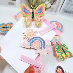 Detail of glitter butterfly and rainbow hair clips with ribbon-wrapped metal bases