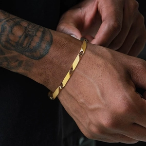 Close-up of a luxury gold stainless steel geometric chain bracelet on a tattooed wrist