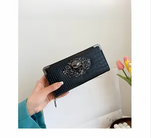 Detail of black crocodile texture wallet with vintage skull ornament and metal corners